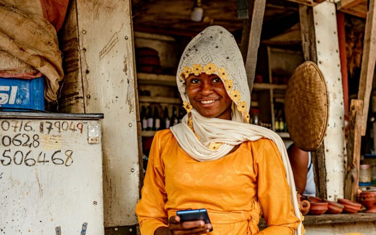 Mfanyabiashara akitumia simu kwenye meza yake ya matunda sokoni